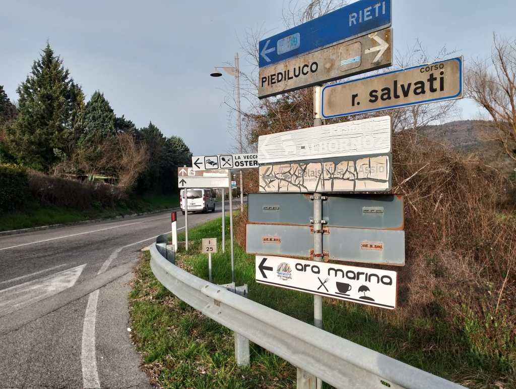 Road signs indicating directions to various locations including Piediluco and Rieti, with a mix of clearly visible and partially obscured information.