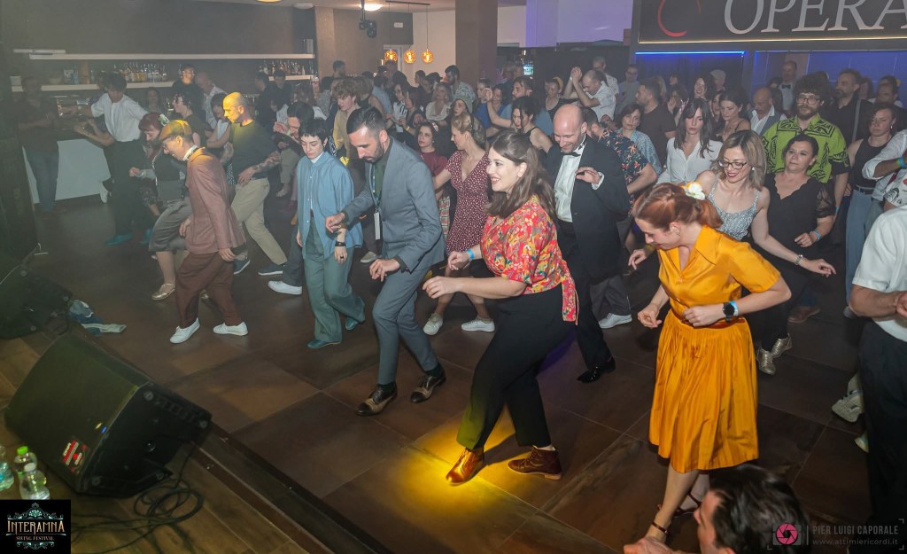 A lively dance floor scene with a diverse group of people enjoying music, dancing in various styles, and dressed in colorful outfits at an event in a venue labeled 'Opera'.