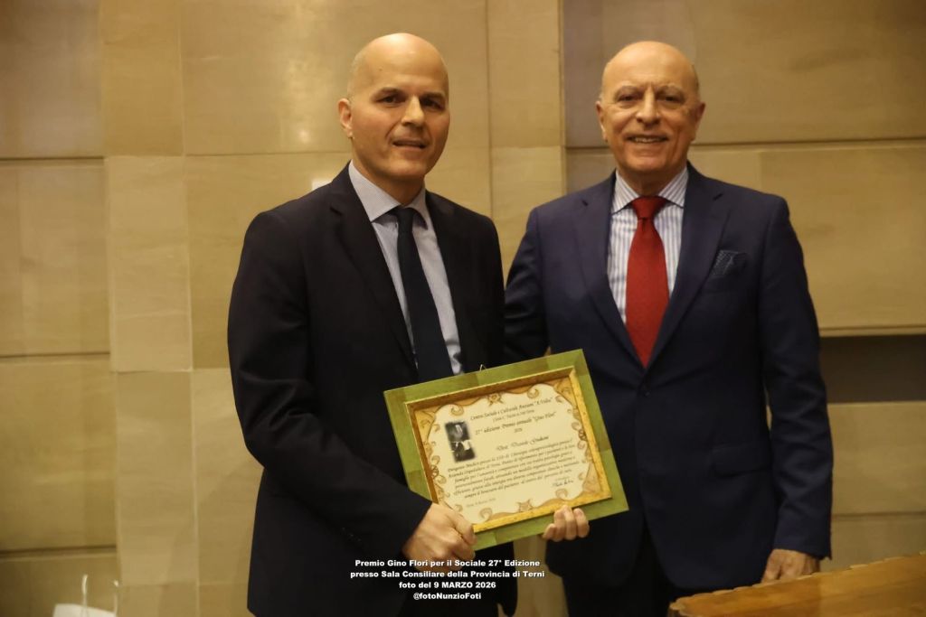 Two men posing together with a certificate award in a formal setting.
