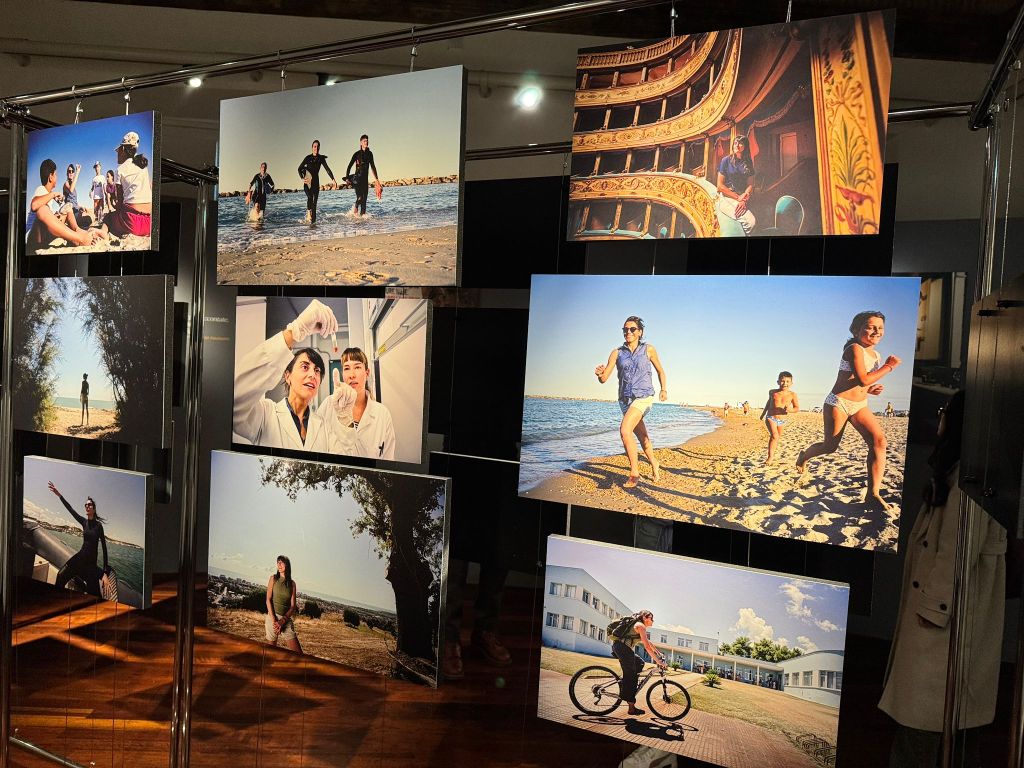 A display of various photographs featuring people at the beach, enjoying leisure activities, and in a laboratory setting. The images showcase individuals swimming, playing on the sand, and conducting experiments, arranged on a metal frame.
