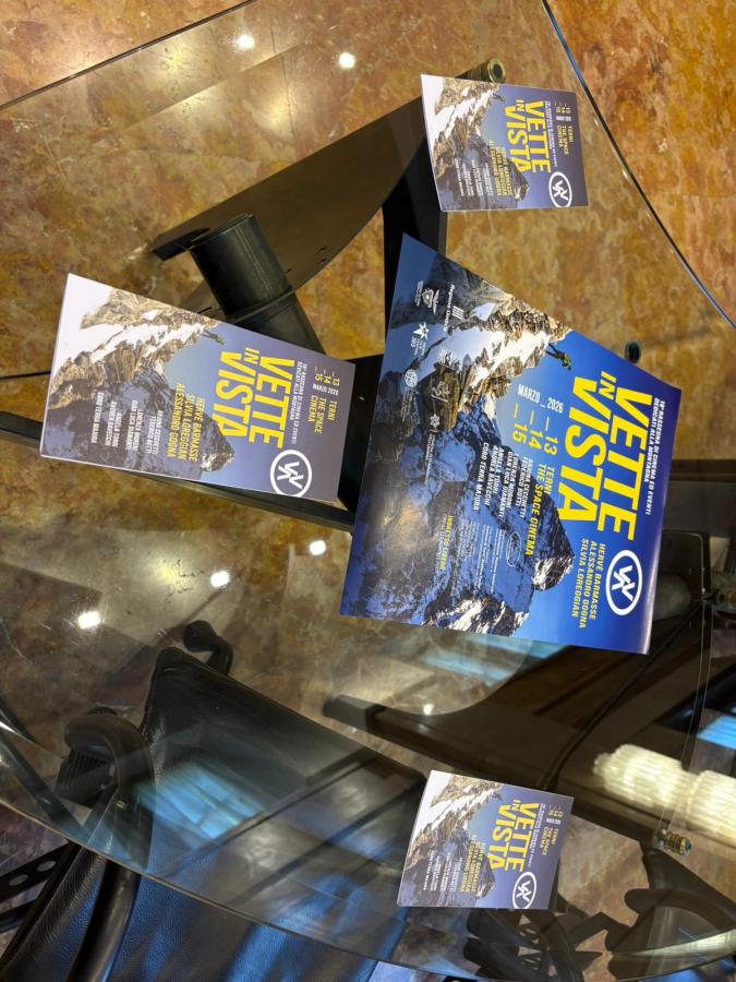 Promotional flyers for the event 'Vette in Vista' displayed on a glass table, featuring mountain imagery and event details.